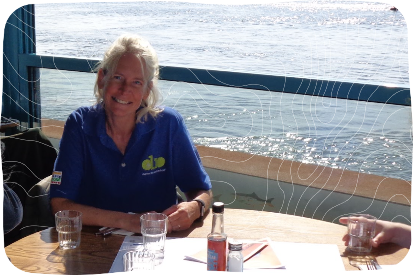 Dementia Adventure Volunteer Jo sitting at a table by the ocean.