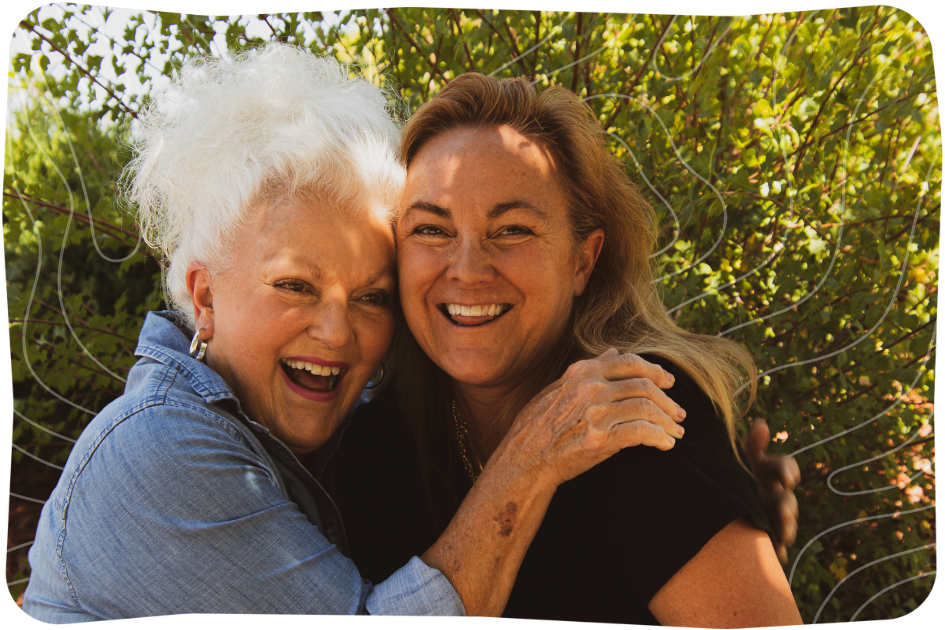 Two women hugging, one elderly with white hair and the other middle-aged.