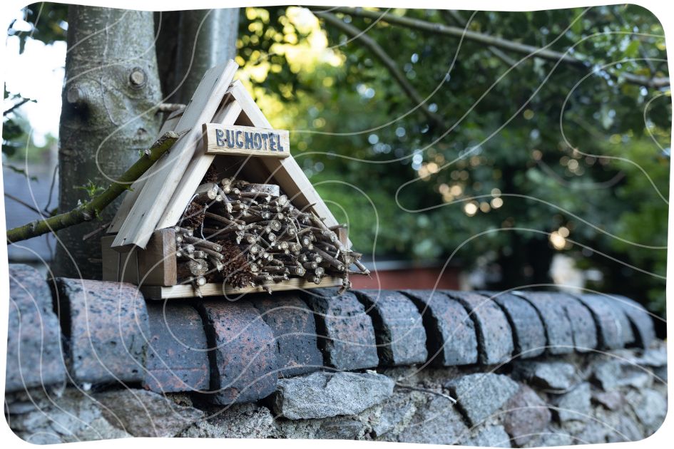 A bug hotel made of a triangular wooden container filled with sticks.